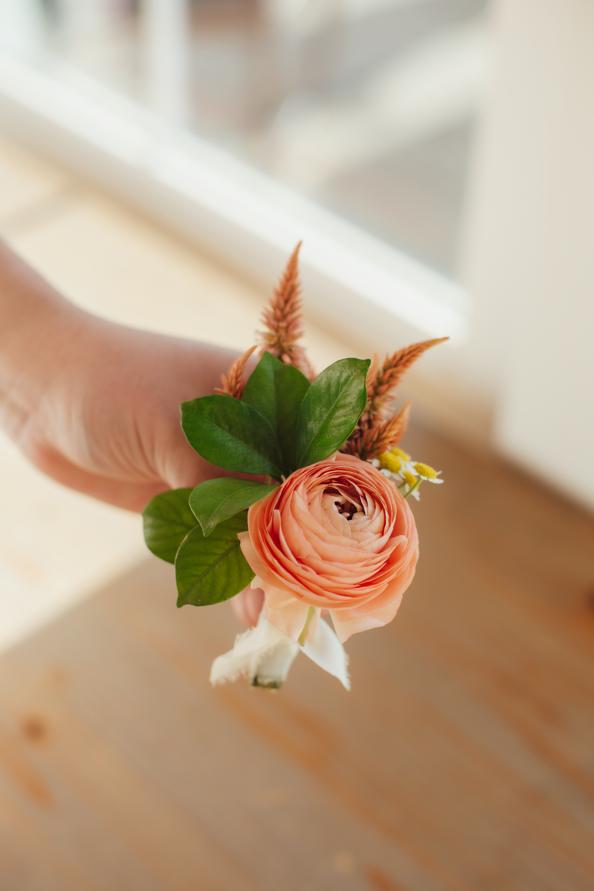 Floral boutonniere with orange flower and green leaves